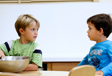 Two boys stirring Playdoh in a bowl.