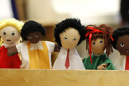 Multi-racial stuffed dolls in a box.