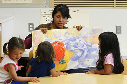 A hispanic teacher instructing children how to read.