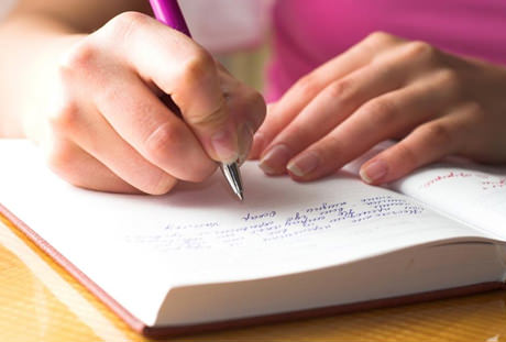 A close-up of a woman writing in a journal.